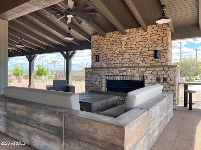 view of patio featuring exterior kitchen, an outdoor stone fireplace, and ceiling fan