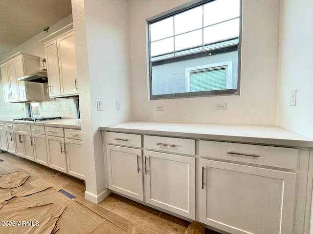 kitchen featuring stainless steel gas stovetop, tasteful backsplash, and white cabinets