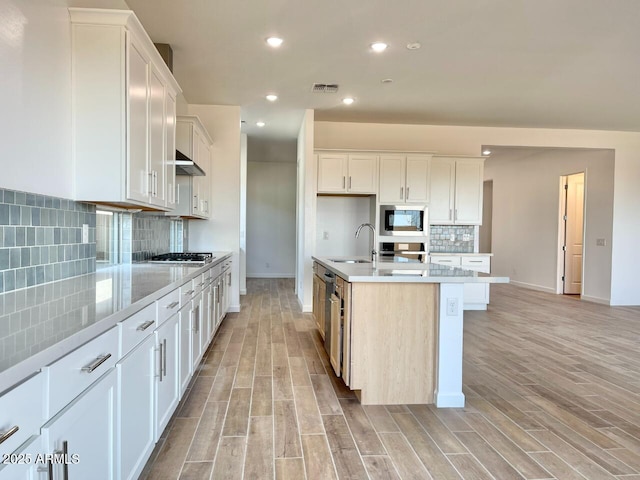 kitchen featuring sink, a kitchen island with sink, white cabinetry, stainless steel appliances, and light hardwood / wood-style floors