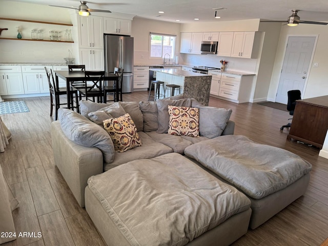 living room featuring ceiling fan, light wood-type flooring, and sink