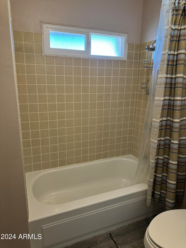 bathroom featuring a wealth of natural light, shower / tub combo with curtain, and toilet