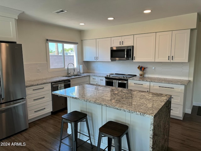 kitchen featuring white cabinets, stainless steel appliances, dark hardwood / wood-style flooring, and a center island