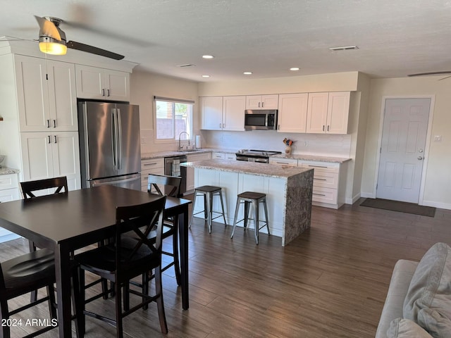 kitchen featuring ceiling fan, a center island, stainless steel appliances, and white cabinets