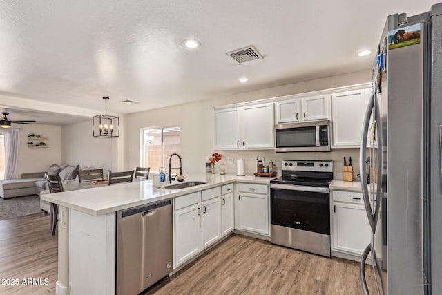 22534 W Pima St, Buckeye, AZ 85326 - kitchen with stainless steel appliances, a sink, open floor plan, white cabinetry, and light wood finished floors