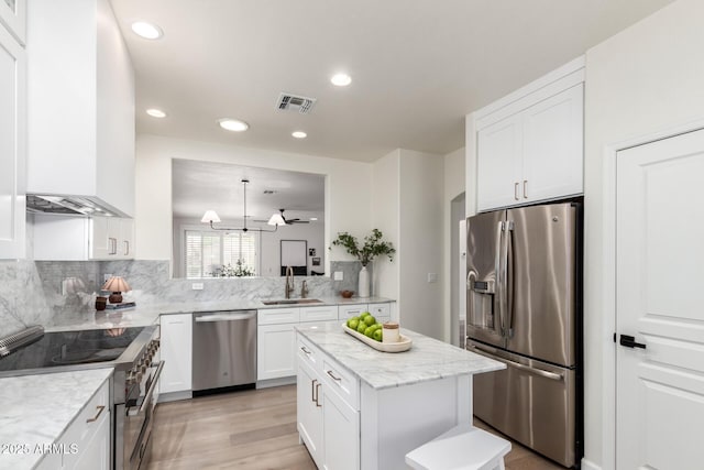 896 E Indian Wells Pl, Chandler, AZ 85249 - kitchen with stainless steel appliances, wall chimney range hood, a sink, white cabinetry, and backsplash