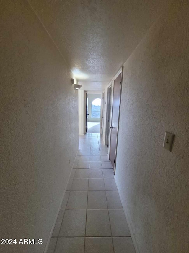 hall with light tile patterned flooring and a textured ceiling