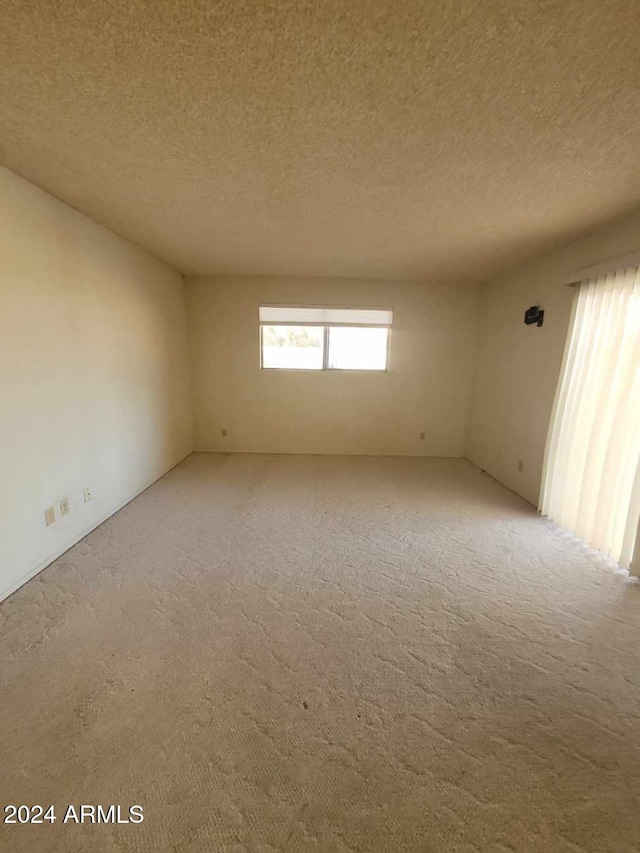 spare room featuring carpet flooring and a textured ceiling