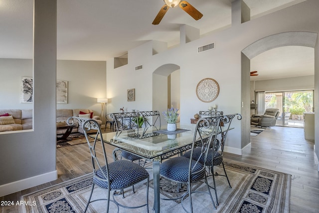 dining space with wood-type flooring, high vaulted ceiling, and ceiling fan