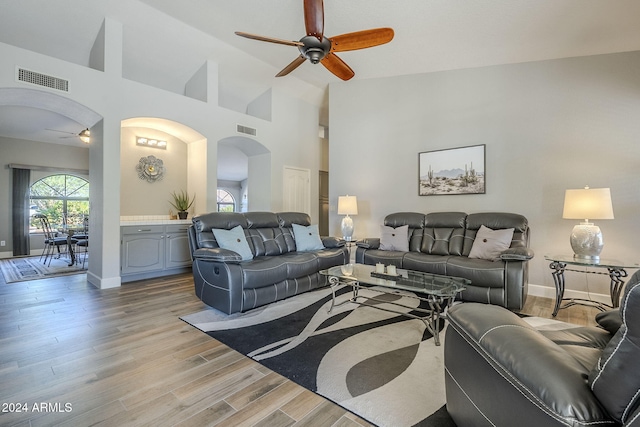 living room featuring ceiling fan, high vaulted ceiling, and light hardwood / wood-style flooring