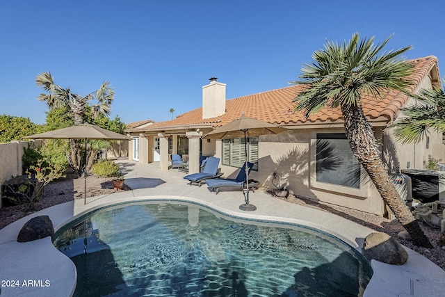 rear view of house with a fenced in pool and a patio