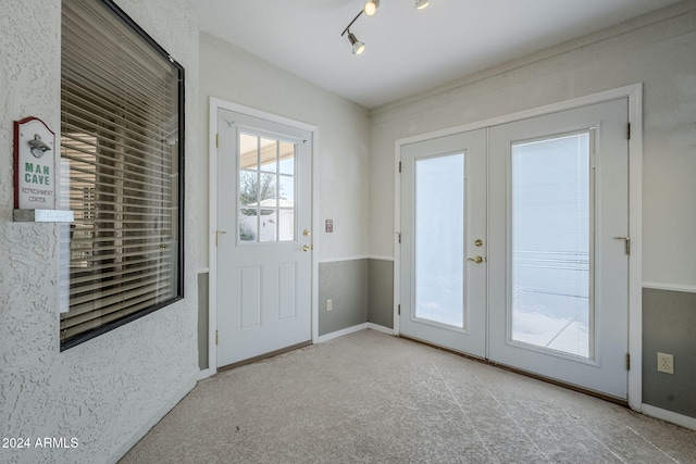 doorway to outside featuring light carpet, french doors, and track lighting