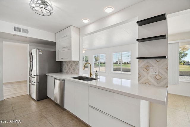 kitchen featuring sink, light tile patterned floors, backsplash, white cabinets, and appliances with stainless steel finishes