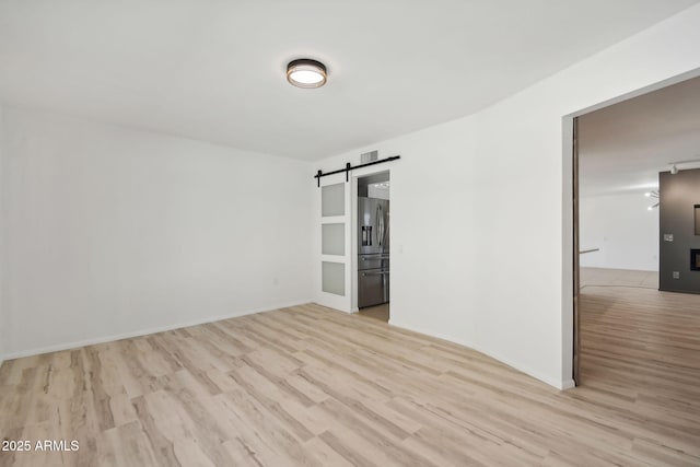 empty room with a barn door and light hardwood / wood-style floors