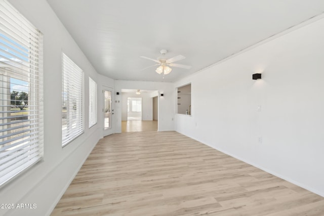 empty room featuring ceiling fan, a healthy amount of sunlight, and light hardwood / wood-style flooring