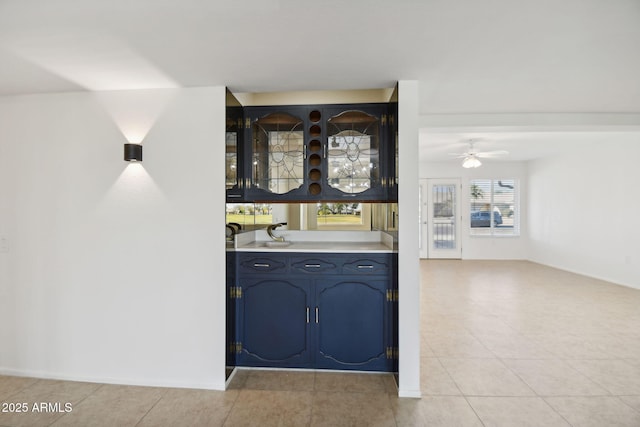 bar featuring blue cabinetry, ceiling fan, and light tile patterned flooring