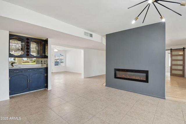 unfurnished living room featuring a barn door, sink, and light tile patterned floors