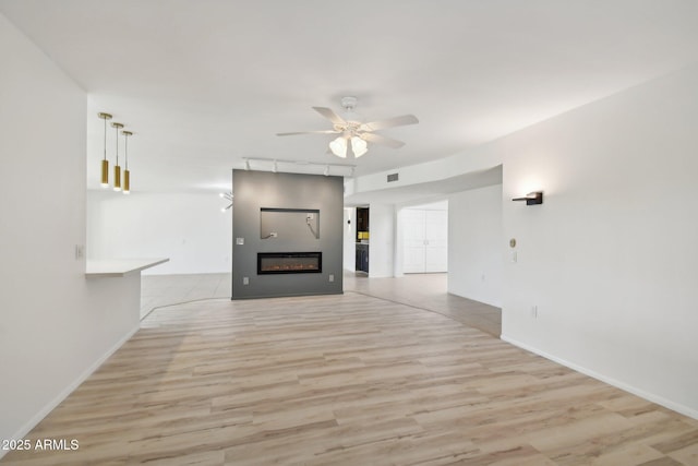 unfurnished living room featuring ceiling fan and light hardwood / wood-style floors