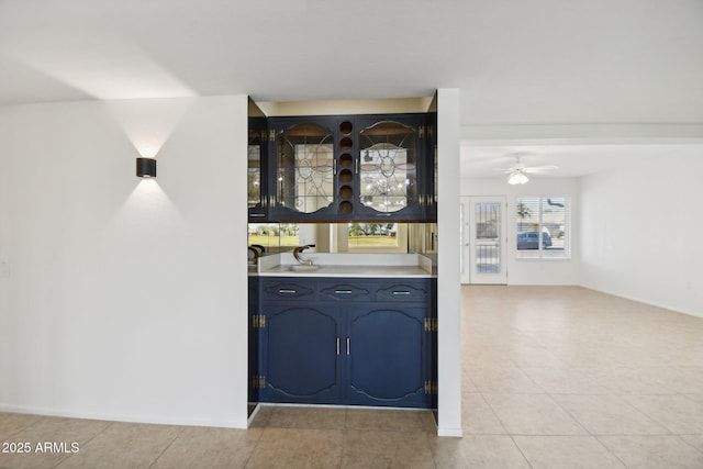 bar featuring ceiling fan, light tile patterned floors, and blue cabinets