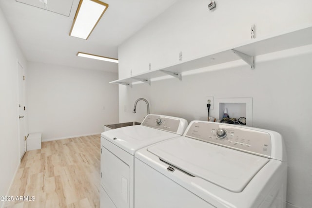 washroom with sink, light wood-type flooring, and independent washer and dryer