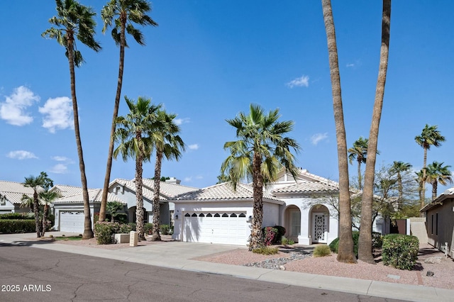 mediterranean / spanish-style house featuring a garage, a tile roof, concrete driveway, and stucco siding