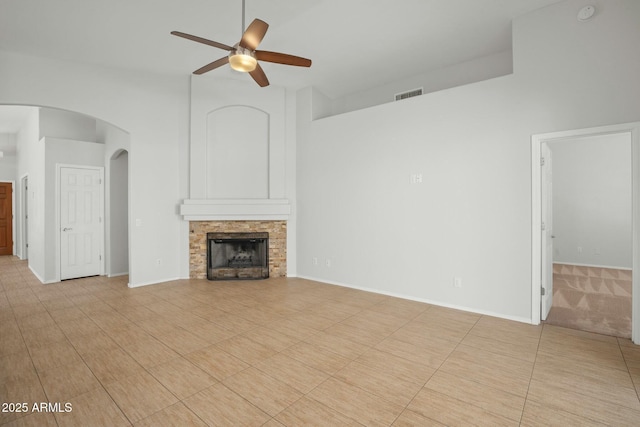 unfurnished living room featuring visible vents, high vaulted ceiling, a ceiling fan, arched walkways, and a fireplace