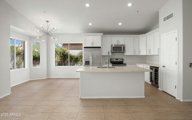 kitchen featuring beverage cooler, visible vents, a sink, stainless steel appliances, and light countertops