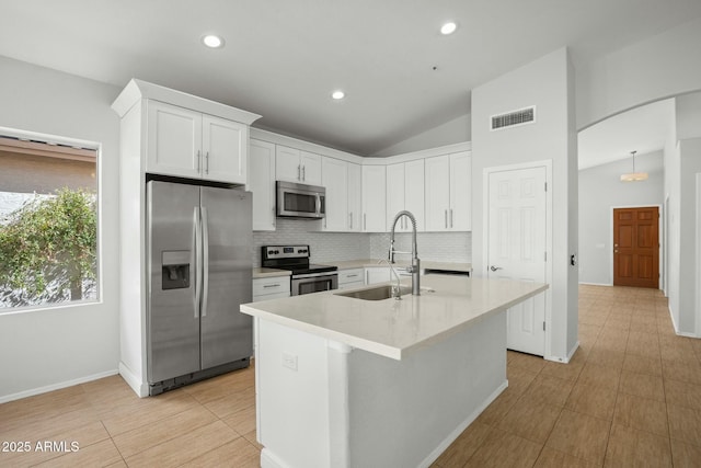 kitchen featuring visible vents, lofted ceiling, arched walkways, a sink, and appliances with stainless steel finishes