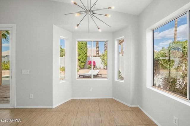 unfurnished room with a chandelier and baseboards