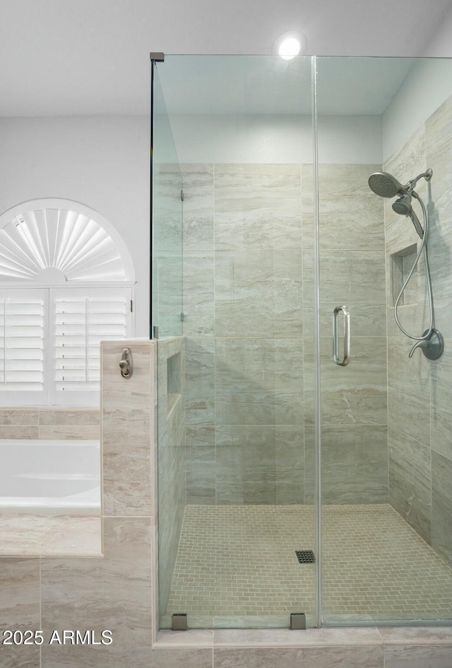 full bathroom featuring a bath and a shower stall