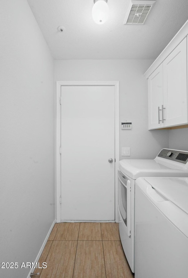 laundry room featuring washer and dryer, cabinet space, and visible vents