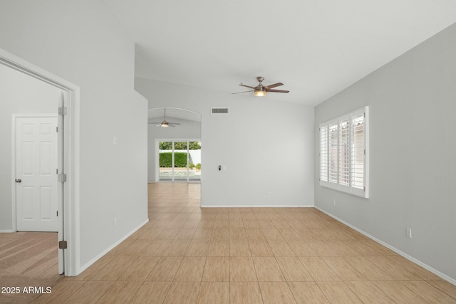 empty room featuring visible vents, baseboards, lofted ceiling, arched walkways, and a ceiling fan