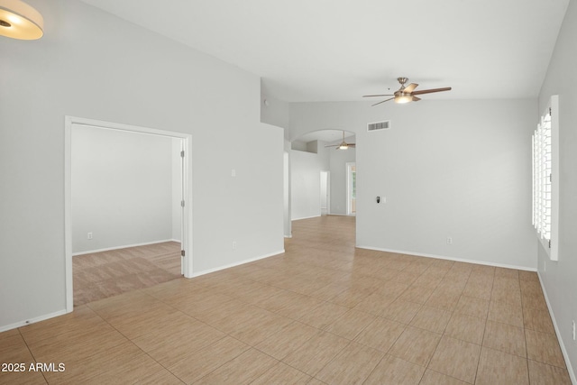 spare room with visible vents, arched walkways, a ceiling fan, and vaulted ceiling