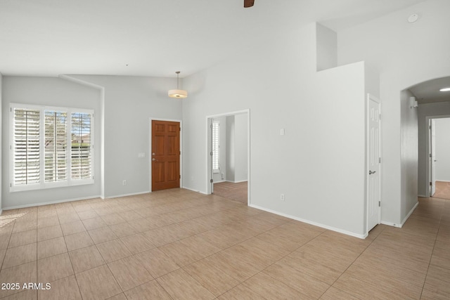 unfurnished room featuring arched walkways, ceiling fan, high vaulted ceiling, and baseboards