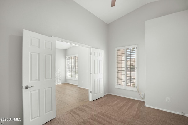 unfurnished bedroom with baseboards, ceiling fan, carpet, tile patterned floors, and high vaulted ceiling