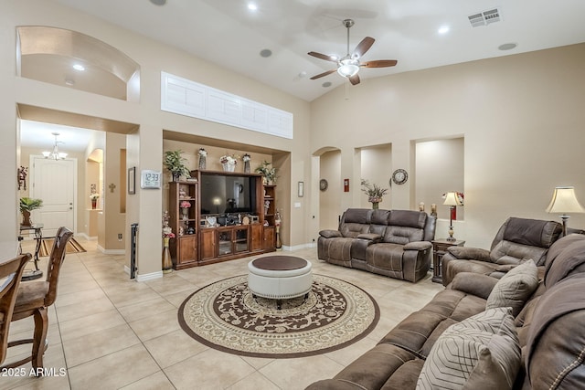 tiled living room with ceiling fan with notable chandelier and high vaulted ceiling