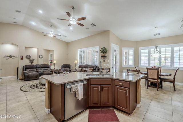 kitchen with hanging light fixtures, light tile patterned floors, stainless steel dishwasher, and a center island with sink