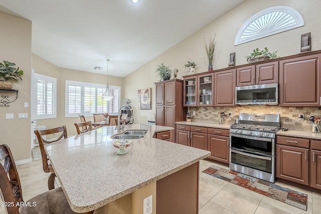 kitchen featuring pendant lighting, sink, appliances with stainless steel finishes, a center island with sink, and decorative backsplash