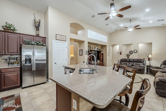 kitchen featuring sink, a breakfast bar area, an island with sink, and stainless steel refrigerator with ice dispenser