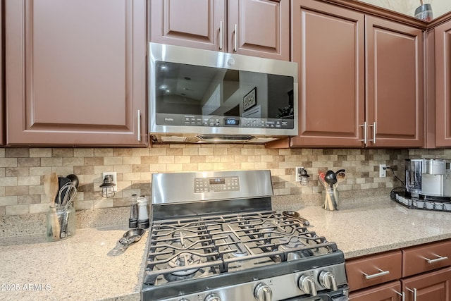 kitchen with stainless steel appliances, light stone countertops, and backsplash