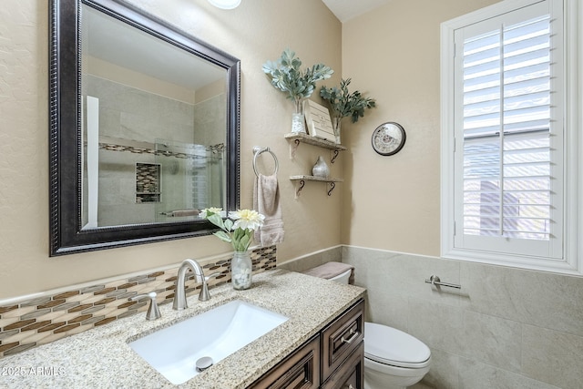 bathroom featuring vanity, toilet, an enclosed shower, and tile walls