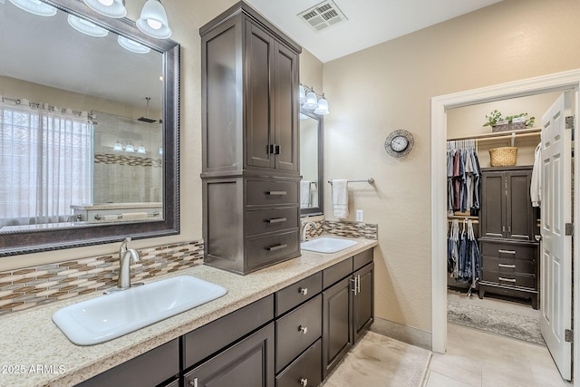 bathroom featuring vanity, a shower, tile patterned floors, and decorative backsplash