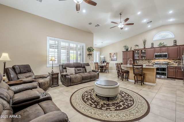 tiled living room featuring ceiling fan, sink, and high vaulted ceiling