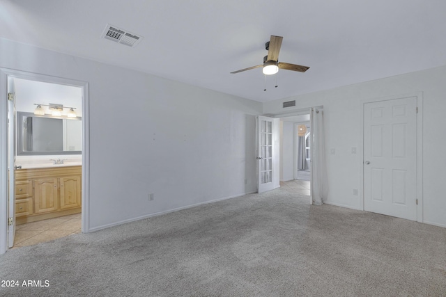 unfurnished bedroom with connected bathroom, ceiling fan, sink, and light carpet