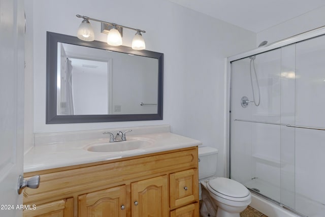 bathroom with vanity, a shower with shower door, and toilet