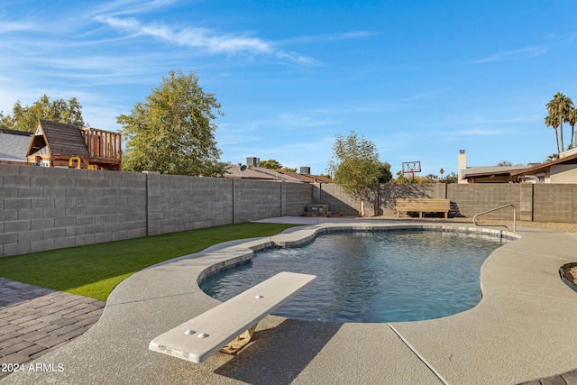 view of swimming pool with a diving board and a yard