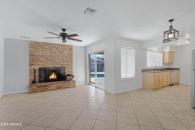 unfurnished living room with a fireplace, light tile patterned floors, ceiling fan, and sink