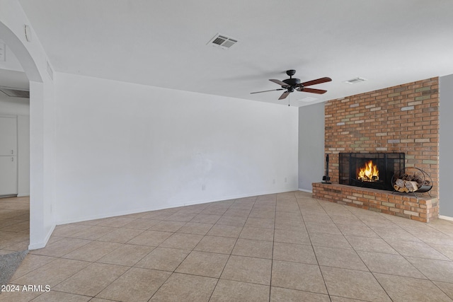 unfurnished living room featuring ceiling fan, light tile patterned floors, and a fireplace