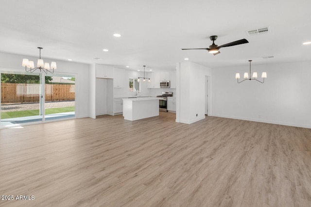 6610 N 15th Ave, Phoenix, AZ 85015 - unfurnished living room featuring light wood-style flooring, ceiling fan with notable chandelier, visible vents, and recessed lighting
