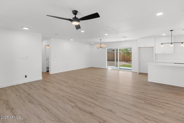 6610 N 15th Ave, Phoenix, AZ 85015 - unfurnished living room featuring ceiling fan with notable chandelier, light wood-style flooring, and recessed lighting