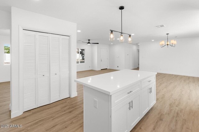 6610 N 15th Ave, Phoenix, AZ 85015 - kitchen featuring ceiling fan with notable chandelier, open floor plan, light wood finished floors, white cabinets, and visible vents